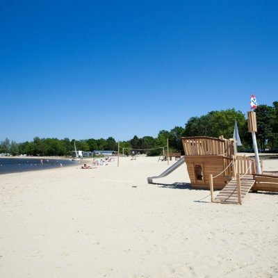 Strand und natürlicher See mit Spielgeräten